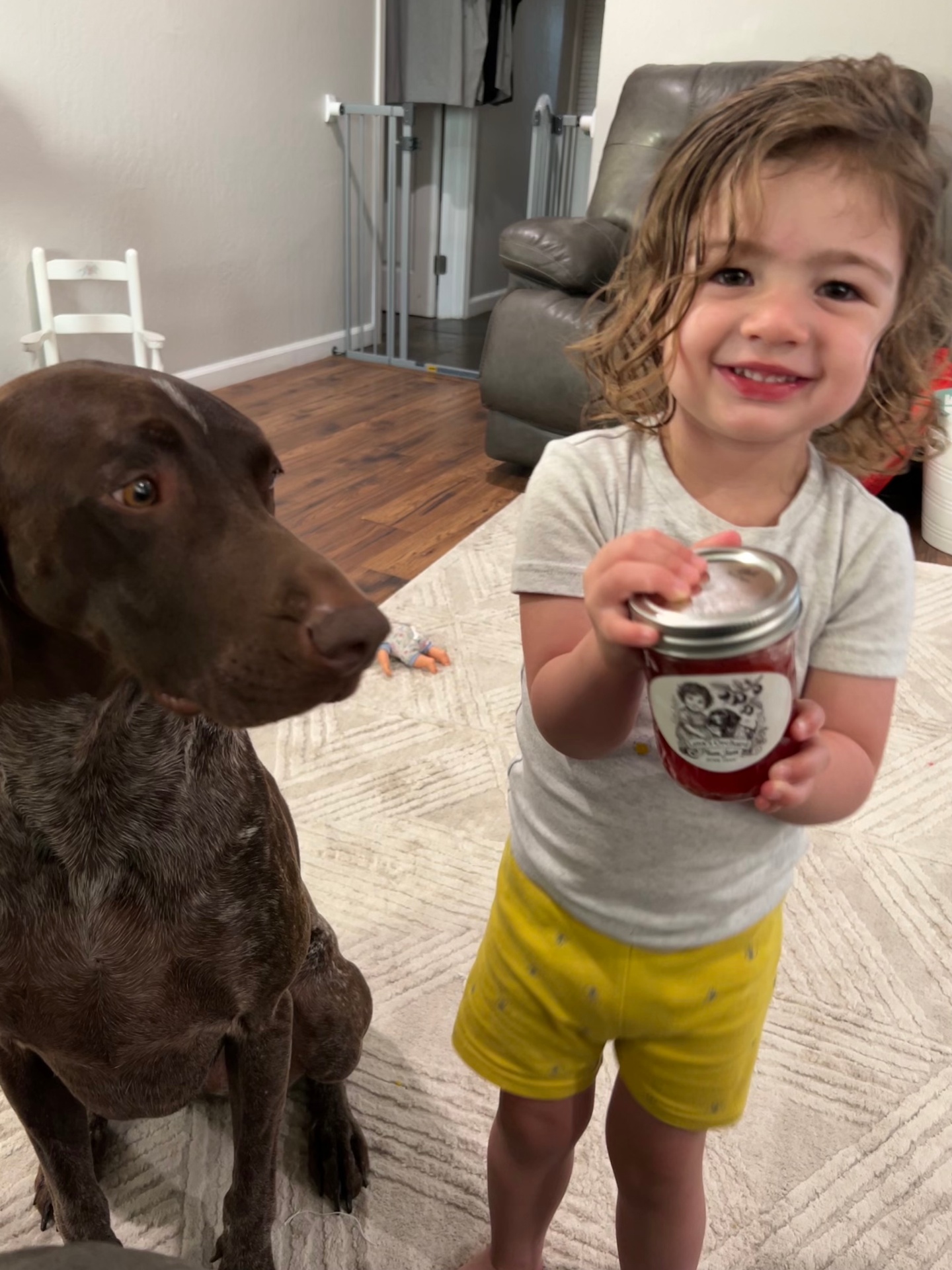 Lena beaming with a jar of plum jam beside Gunner the German Shorthaired Pointer