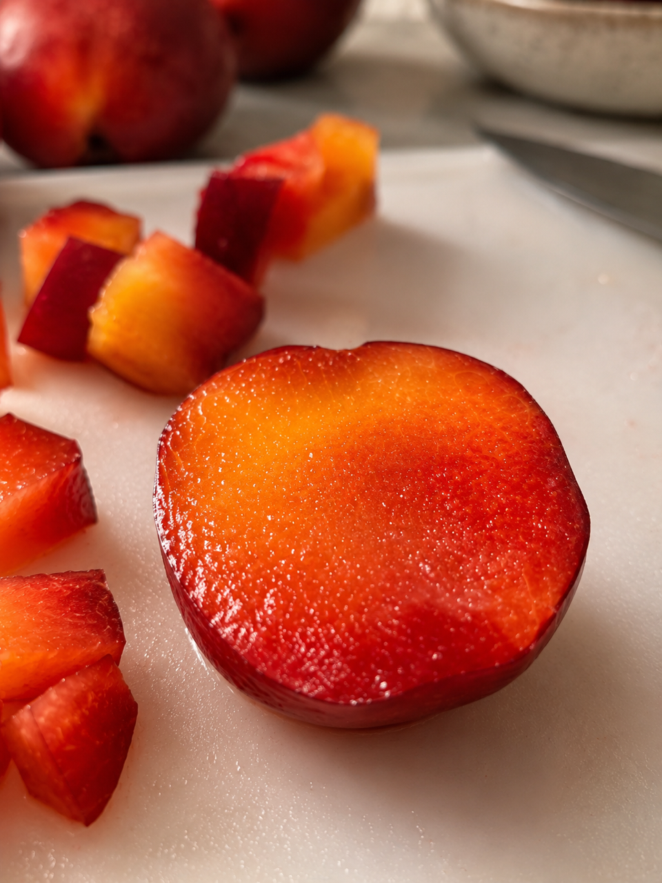 Halved Santa Rosa plum revealing sunset-orange flesh on the cutting board